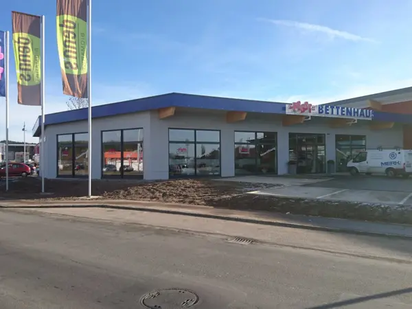 Außenansicht Möbelhaus Bettenhaus mit Schaufenstern, Fahnen und Parkplatz
