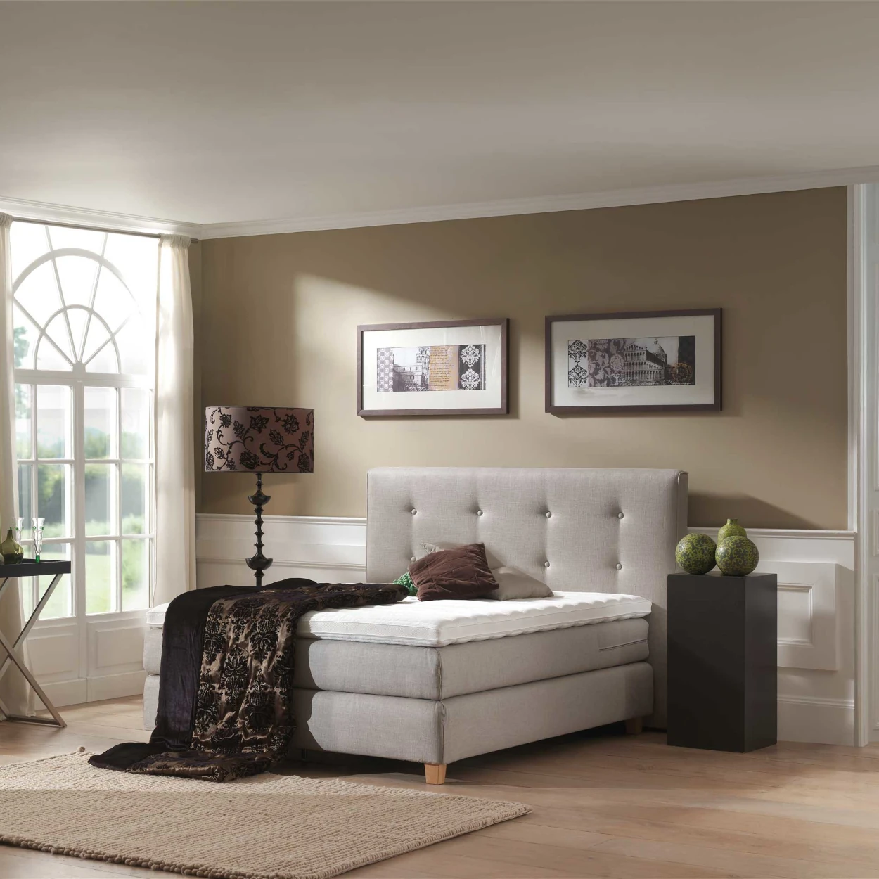 Modernes Boxspringbett mit grauem Kopfteil in elegant eingerichtetem Schlafzimmer.